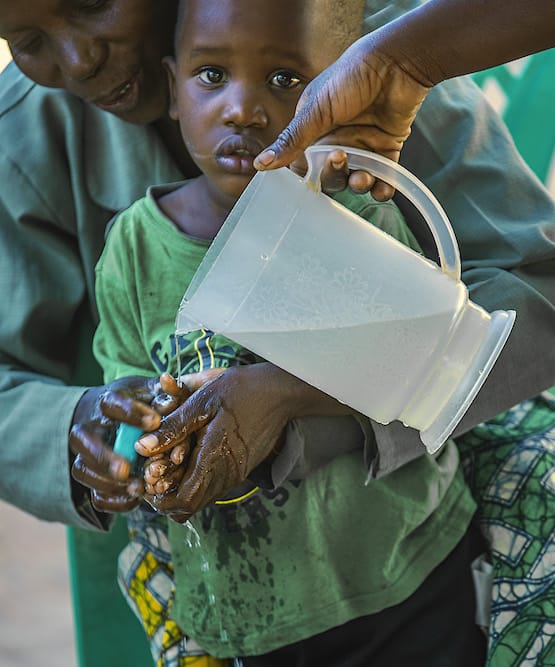 Woman helping young boy wash his hands