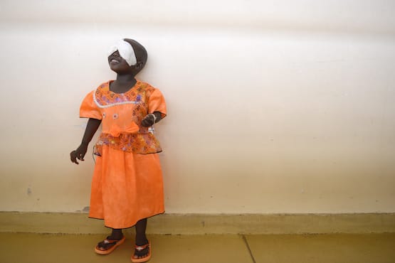 Young blind girl in orange dress with gauze over her eyes