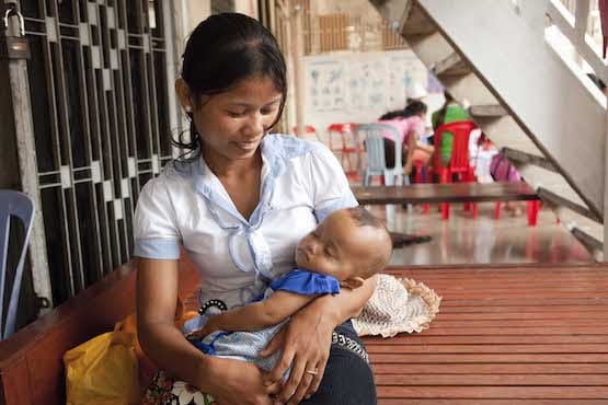 Cambodian mother smiling down at baby in her arms