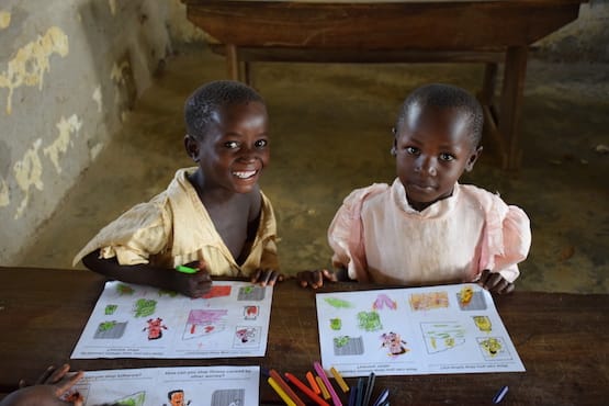 A young boy and girl coloring worksheets at school