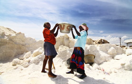 A man and a woman from GAIN lifting a large bucket of salt