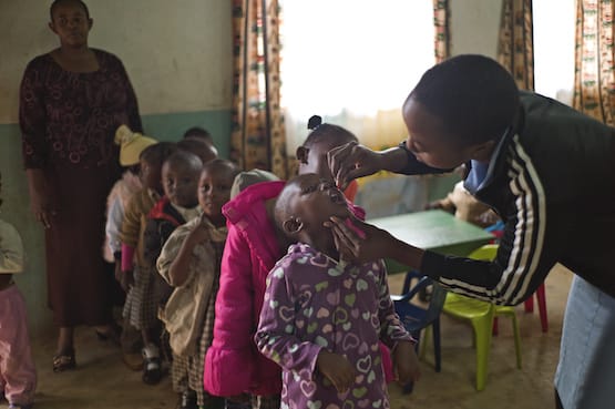 Woman in Kenya giving child Vitamin A through Helen Keller International