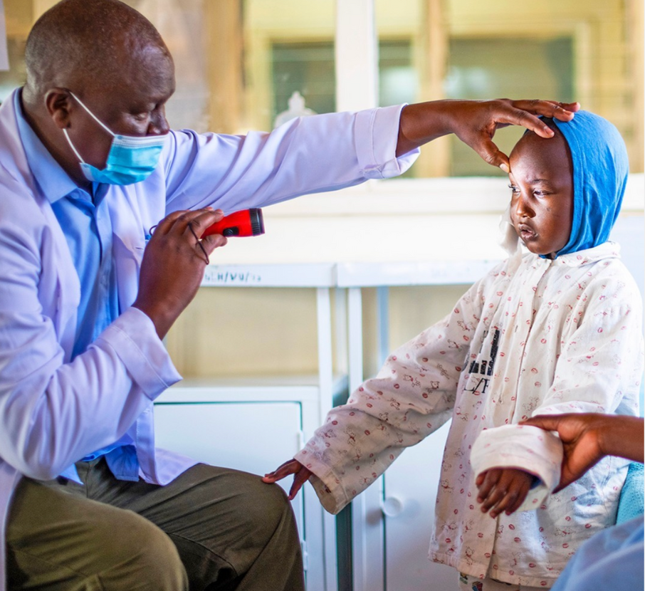 A Fred Hollows eye doctor shining a light in a young patient's eyes