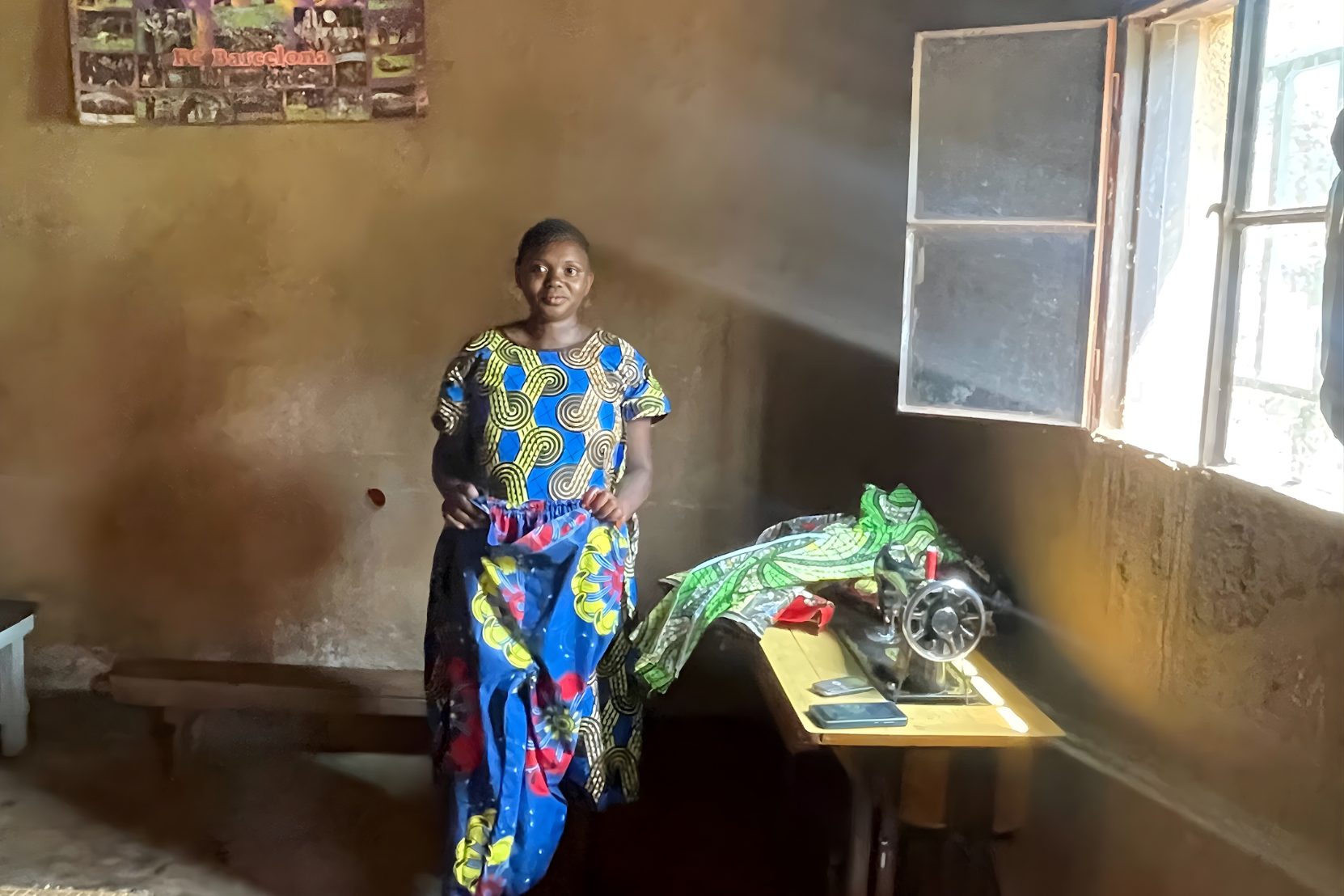 Mushimiyimana Argentine showcasing clothes she tailors for her business group. Village Enterprise recommended charities