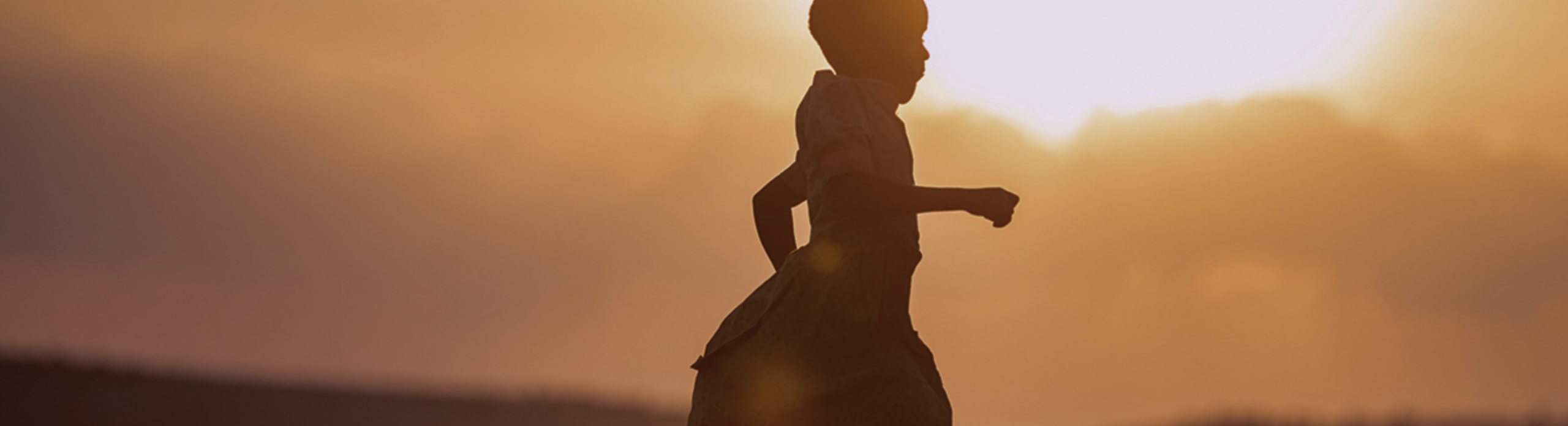 A woman silhouetted against a sunset sky